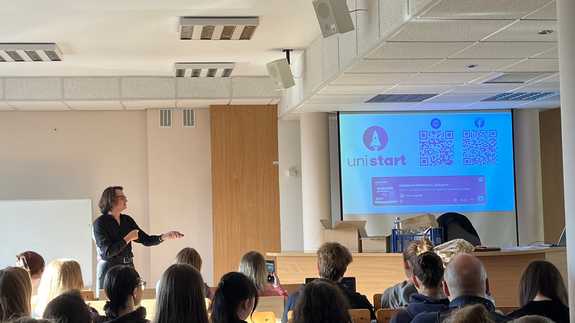 Zdjęcie ze szkoleń, na którym znajdują się studenci siedzący w sali wykładowej; na projektorze wyświetlane jest logo UniSTART.