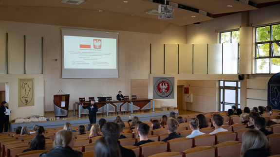 Zdjęcie ze szkoleń, na którym znajdują się studenci siedzący w sali wykładowej; na projektorze wyświetlana jest informacja o dofinansowaniu ze środków budżetu państwa.