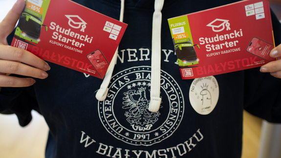 Studentka w bluzie uniwersyteckiej trzymająca dwa startery studenckie.