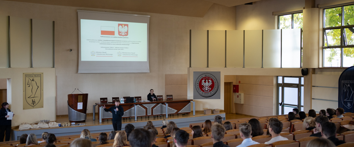 Zdjęcie ze szkoleń, na którym znajdują się studenci siedzący w sali wykładowej; na projektorze wyświetlana jest informacja o dofinansowaniu ze środków budżetu państwa.