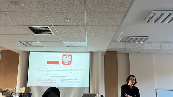 Zdjęcie ze szkoleń, na którym znajdują się studenci siedzący w sali wykładowej; na projektorze wyświetlana jest informacja o dofinansowaniu ze środków budżetu państwa.